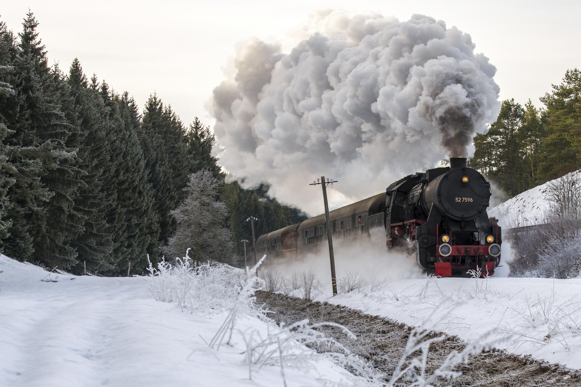 Nostalgiefahrten mit dem Dampfzug in Münsingen im Biosphärengebiet Schwäbische Alb. Eine historische Dampflok fährt durch eine Winterlandschaft. Sie zieht eine lange Dampf-Spur hinter sich her.