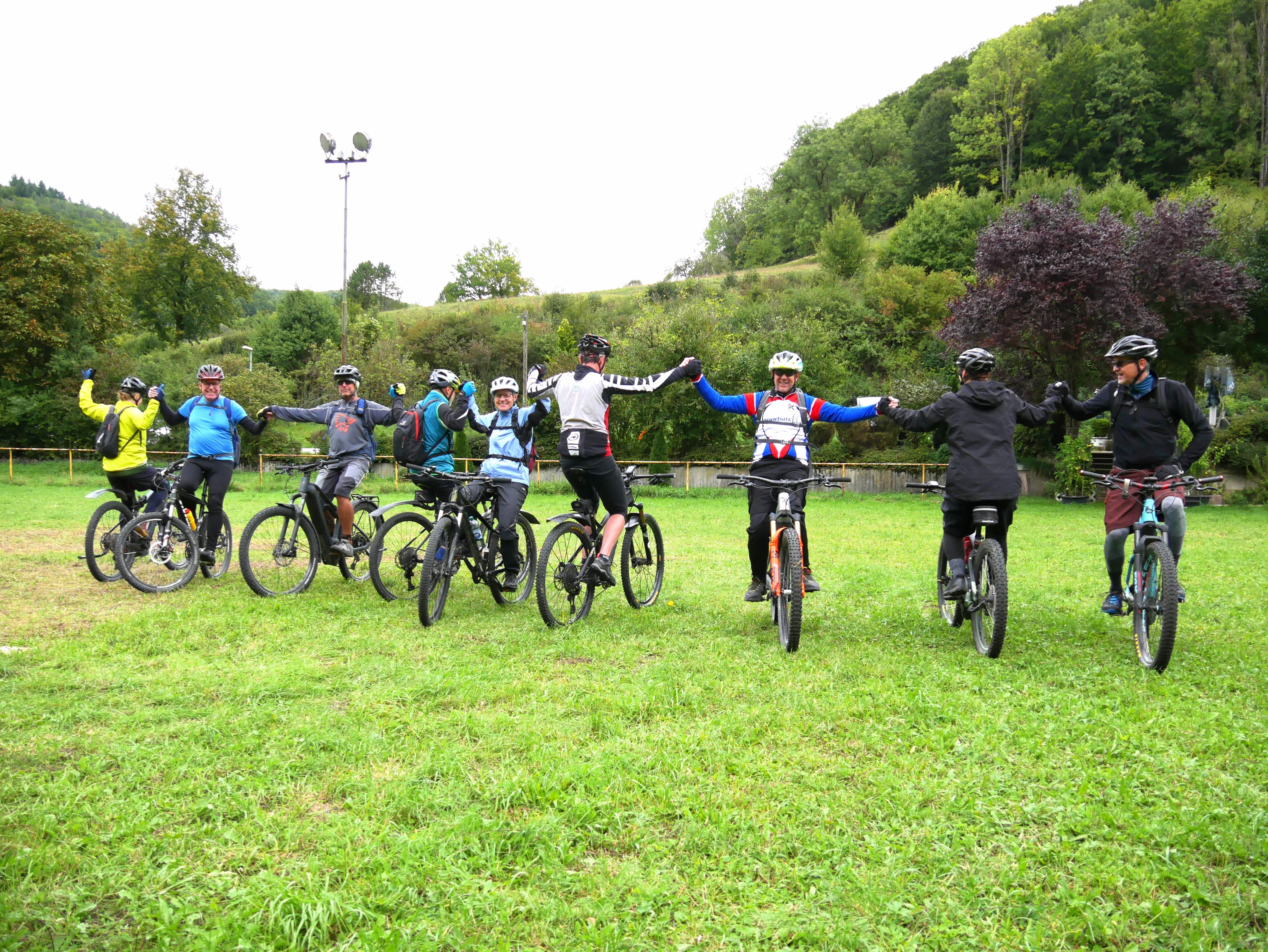 Mountainbike Technikktraining im Rahmen der Gea-Radserie im Biosphärengebiet Schwäbische Alb. Mehrere Radfahrer*innen stehen mit Fahrrädern nebeneinander in entgegengesetzte Richtungen und halten sich an den Händen.