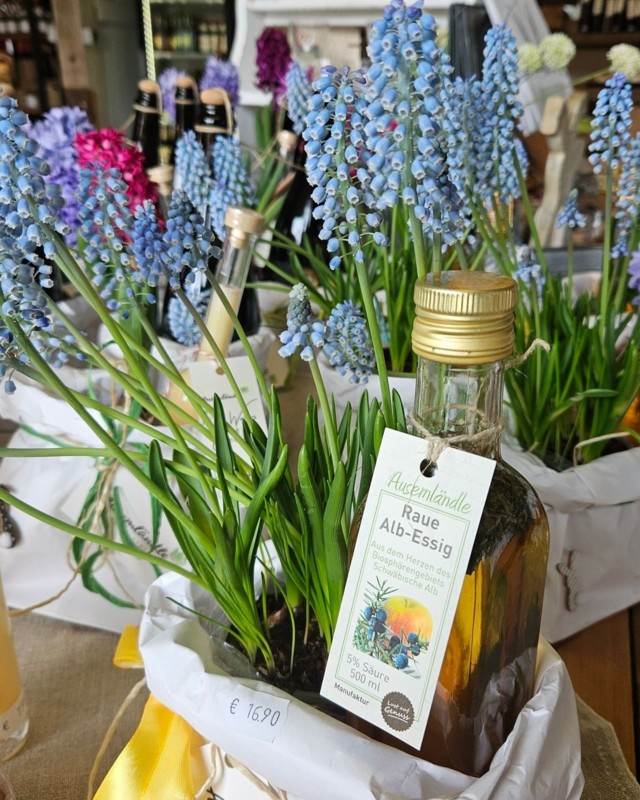 Geschenke mit regionalen Produkten aus Münsingen im Biosphärengebiet Schwäbische Alb. Mehrere Körbchen mit Frühlingsblumen und einem Essig von Ausemländle.