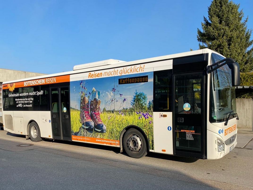 Der Rad- Wanderbus von Münsingen durch das Biosphärengebiet Schwäbische Alb. Ein Bus mit Werbung von Bottenschein Reisen steht auf einem Parkplatz.