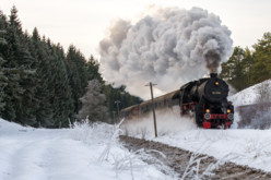 Nostalgiefahrten mit der Dampflok der Schwäbische Alb-Bahn in Münsingen im Biosphärengebiet Schwäbische Alb. Eine historische Dampflok fährt durch eine Winterlandschaft. Sie zieht eine lange Dampf-Spur hinter sich her.
